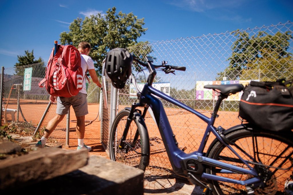 A man came to tennis practice on his bicycle.